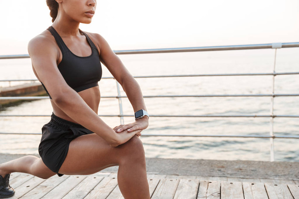 Image of energetic young woman squatting and stretching her body - Photo, Image