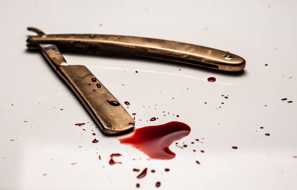 Dangerous razor bloodied on a light background. Razor with bloody smudges on the blade. - Photo, Image