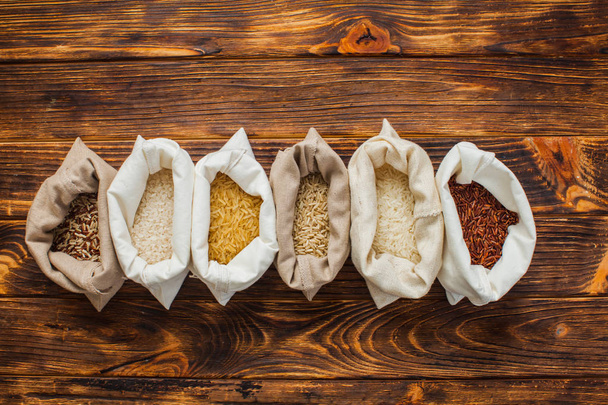 Different rice types in textile bags on wooden background - Zdjęcie, obraz