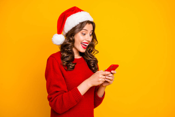 Photo of pretty lady holding telephone in hands wear knitted pullover and santa hat isolated yellow background - Foto, Imagem