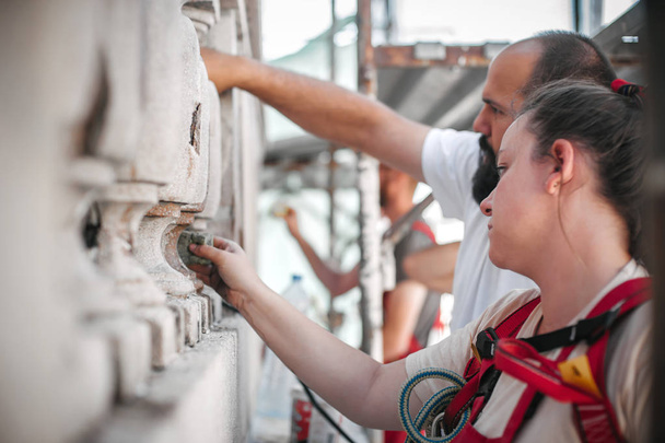Dva dělníci stojící na lešení a obnovují starou fasádu budovy - Fotografie, Obrázek