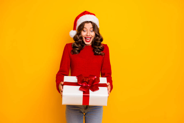 Amazing lady holding large giftbox in arms wear knitted jumper and santa hat isolated yellow background - Fotografie, Obrázek