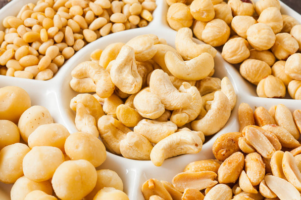 White plate with variety of nuts close up - Fotó, kép