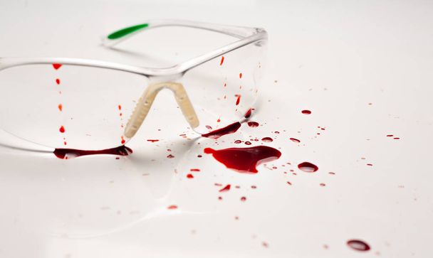 Sicherheitskonzept. Blut auf dem Schreibtisch, Schutzbrille. - Foto, Bild