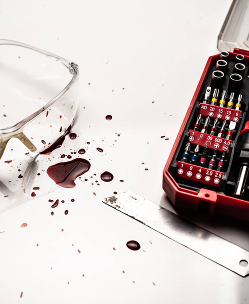 Safety breach concept. Blood on the desktop, safety glasses. - Photo, Image