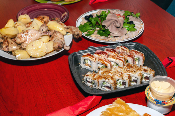 Potato and meat dishes, fish dishes and sushi are served on the  - Photo, Image