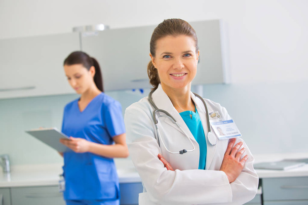 Portrait of confident doctor standing against nurse at clinic - Foto, afbeelding