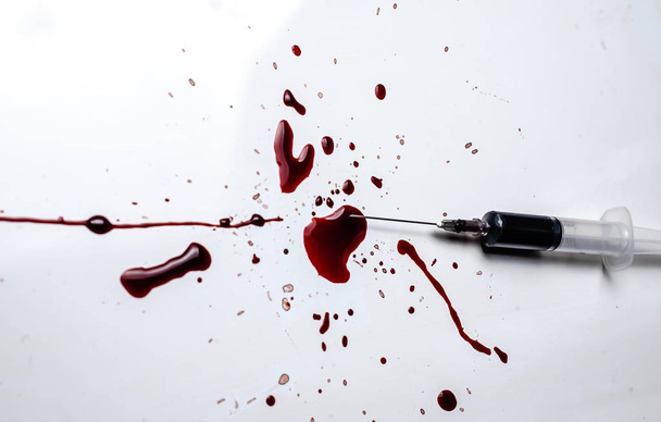 Syringe and blood splatter on a white background. A lot of blood and a syringe. - Photo, Image