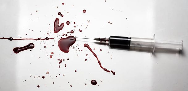 Syringe and blood splatter on a white background. A lot of blood and a syringe. - Foto, Imagen