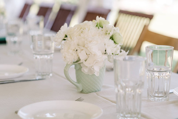 Een boeket van witte zachte rozen in een kleine mok-stijl vaas. - Foto, afbeelding