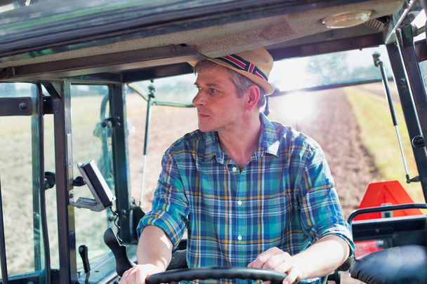 luottavainen viljelijä, joka ajaa traktoria maatilalla
 - Valokuva, kuva