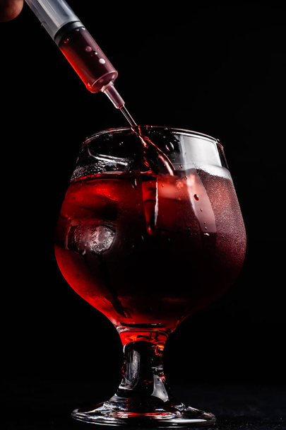 Bloody alcoholic cocktail with a syringe. - Фото, зображення