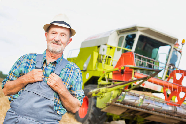Portrait of confident senior farmer standing against tractor at farm - Foto, Imagem