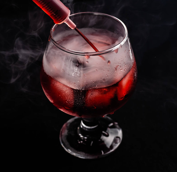 Bloody alcoholic cocktail with a syringe. - Foto, imagen