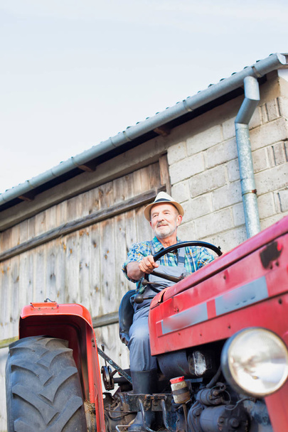 confident farmer driving tractor at farm - Фото, зображення