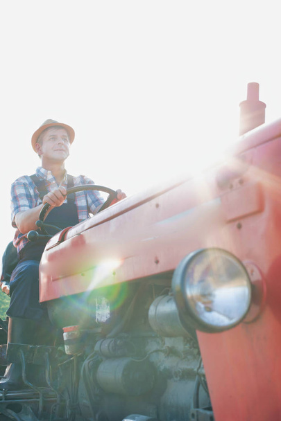 confident farmer driving tractor at farm - Фото, изображение
