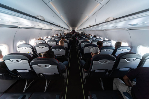 乗客と飛行機のキャビンの座席。フライトの遅延や欠航なしで新しい最も安い低コストの航空会社のエコノミークラス。他の国への旅行. - 写真・画像