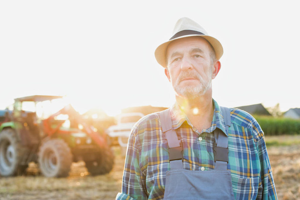 Portrait of confident senior farmer standing against tractor at farm - Fotografie, Obrázek