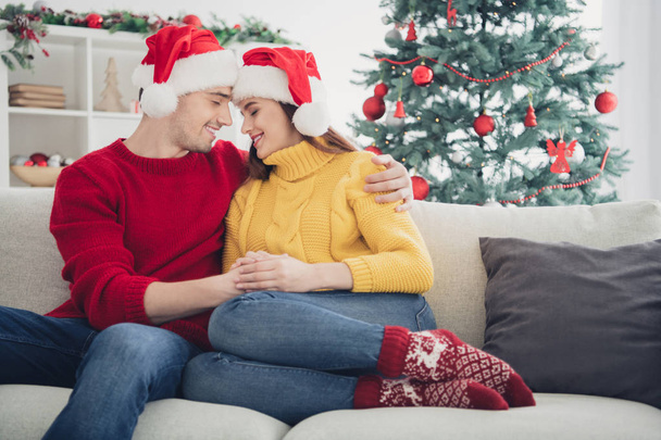 You are my world... Portrait of two romantic people spouses hug feel romance sit on divan in christmas time newyear vacation wear santa claus hat in house with noel decoration ornaments - Fotó, kép