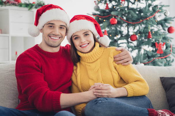Holly christmas. Portrait of two people spouses feel romance hug sit on couch enjoy 2020 newyear holidays in house with x-mas decoration - Foto, afbeelding