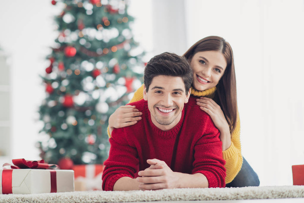 Close up photo of two people spouses wear red yellow comfy jumpers lying on floor enjoy christmas party newyear celebration feel bonding in house with new year decoration ornaments - Fotografie, Obrázek