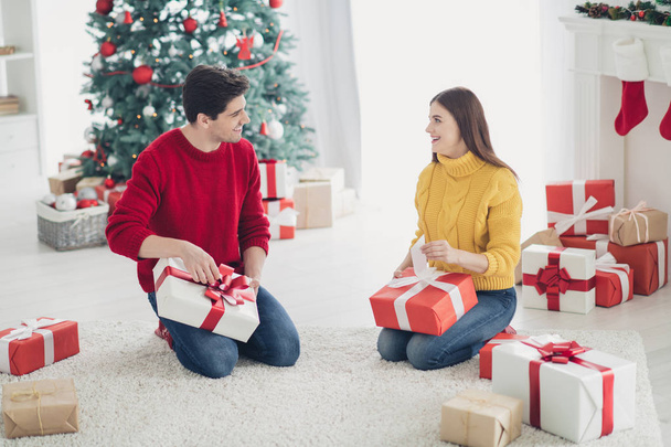 Full size photo of two romantic people open presents from santa claus enjoy christmas tradition vacation sit on floor in house with x-mas decoration socks indoors - Foto, Bild