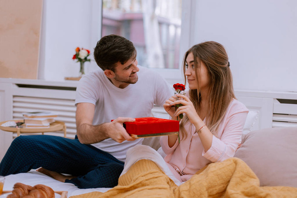 Valentines morning boyfriend giving a gift for his girlfriend she is very happy - Fotó, kép