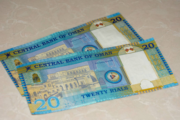 20 Rial rachunki pieniężne, waluta Oman zauważa rozłożone na pół białe tło.. Wymiana pieniądza. - Zdjęcie, obraz