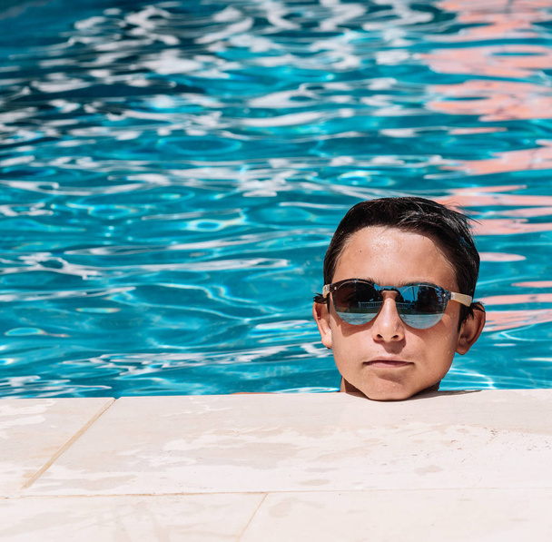 Pre-adolescenti in posa con occhiali da sole sul bordo della piscina
 - Foto, immagini