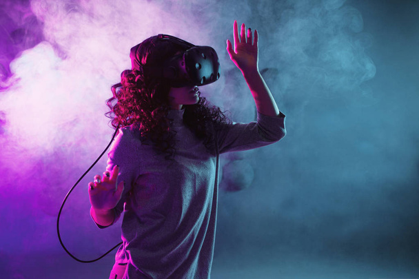 Wirtualna rzeczywistość gry. Dziewczyna w hełmie VR gra lub eksploruje środowisko. - Zdjęcie, obraz
