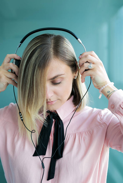 Beautiful blonde in silver headphones listens to music. Stylish  - 写真・画像