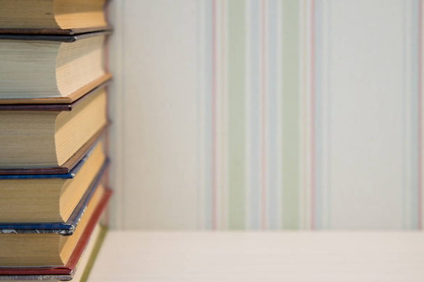 A neat stack of books on the edge of the white table - 写真・画像