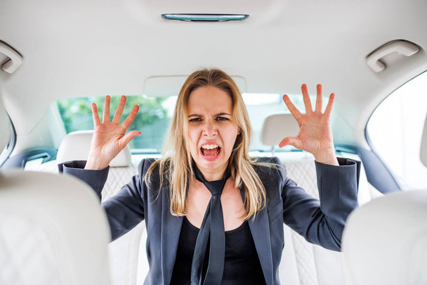 Young frustrated businesswoman sitting in car, grimacing. - Fotoğraf, Görsel