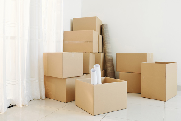Many opened and closed cardboard boxes in corner of empty room of new house - 写真・画像