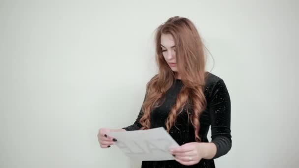 Mädchen mit braunen Haaren in schwarzem Kleid über isoliertem weißem Hintergrund zeigt Emotionen - Filmmaterial, Video