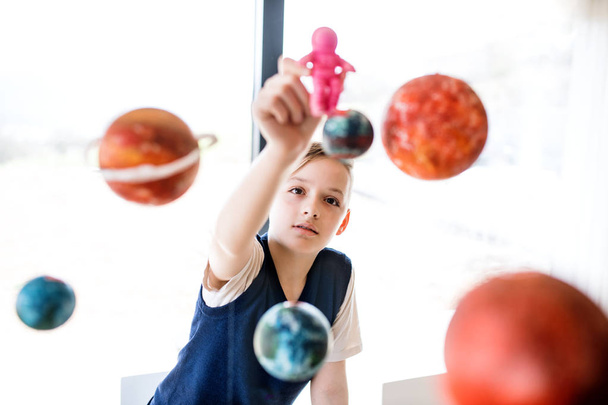 A small boy with model of solar system indoors. - Zdjęcie, obraz