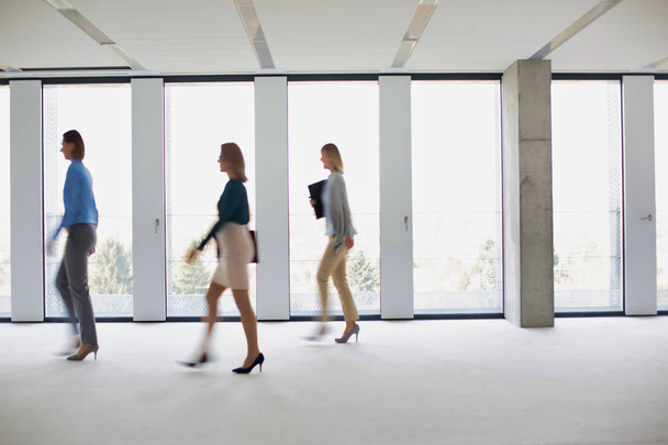 Ομάδα επιχειρηματιών που περπατούν αργά σε άδεια γραφεία - Φωτογραφία, εικόνα