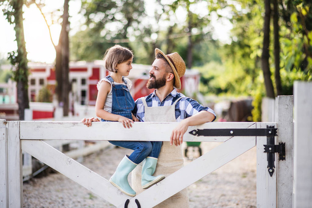 A portrait of father with small daughter outdoors on family farm. - Foto, imagen