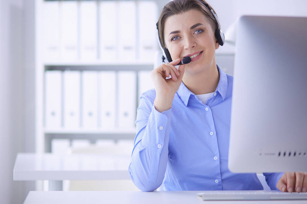 Serious pretty young woman working as support phone operator with headset in office - Foto, immagini