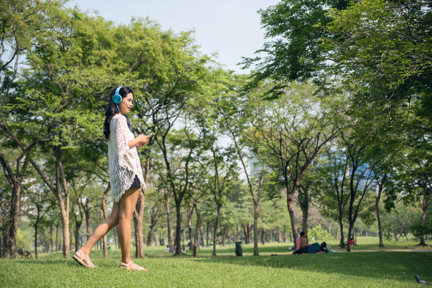Asian girl listen music in park - Foto, imagen