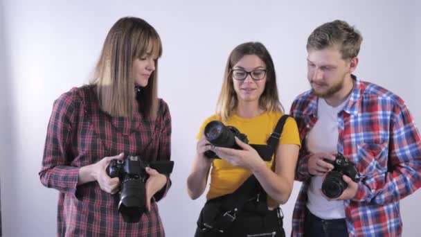 camarógrafos, jóvenes especialistas estudian el dispositivo de las cámaras SLR durante la lección de fotografía en la escuela de fotografía
 - Imágenes, Vídeo