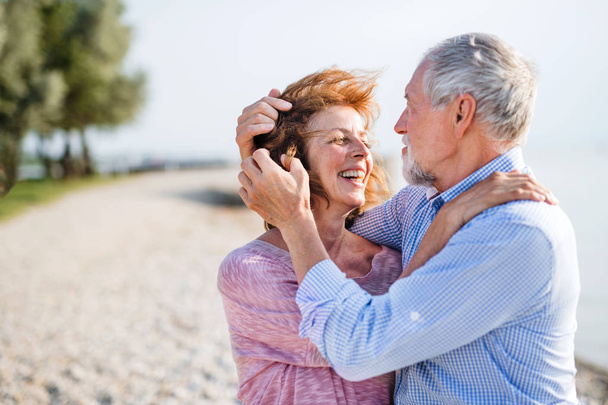 Senior couple on a holiday on a walk by the lake, hugging. - Foto, imagen