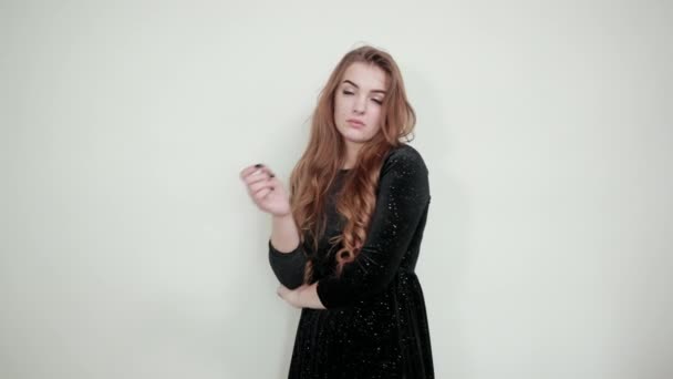 fille aux cheveux bruns en robe noire sur fond blanc isolé montre des émotions
 - Séquence, vidéo