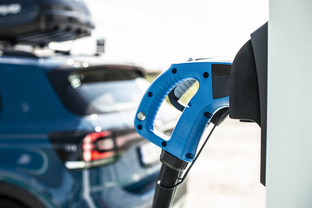 Elektrische auto op benzinestation. Blauwe auto en elektrische stekker voor char - Foto, afbeelding