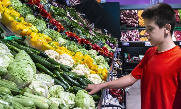 Child selecting vegetables on shelf in supermarket. - Fotoğraf, Görsel
