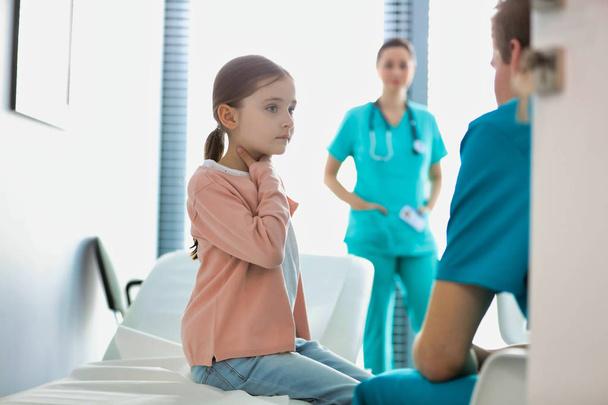 Nurse talking to girl sitting at hospital - Фото, зображення