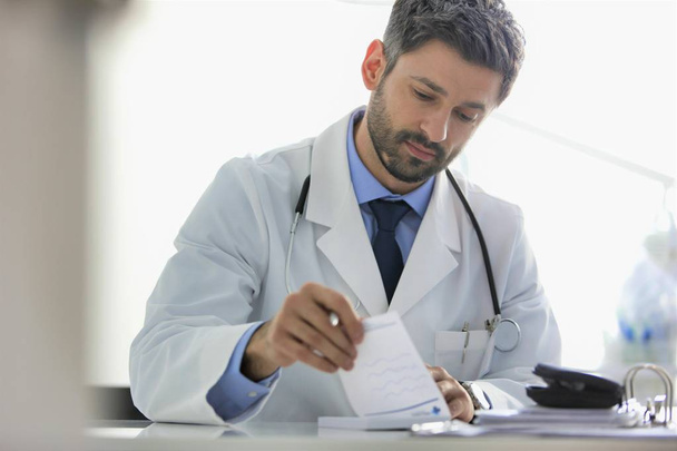 Doctor writing prescription at desk in hospital - Foto, Imagen