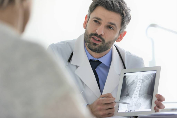 Doctor explaining x-ray on digital tablet to patient at desk in  - Fotoğraf, Görsel