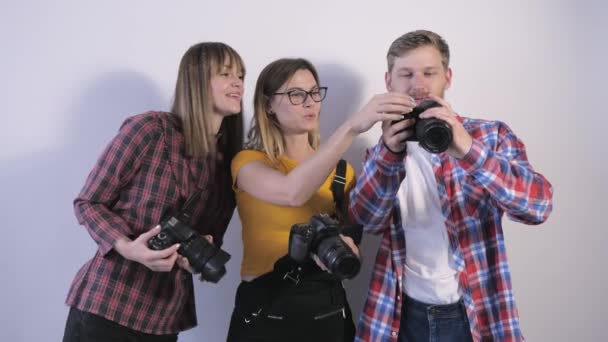 νέοι επαγγελματίες με ψηφιακές φωτογραφικές μηχανές στα χέρια συζητούν φωτογραφίες που τραβήχτηκαν κατά τη διάρκεια σεμιναρίου για φωτογράφους σε φωτογραφικό στούντιο - Πλάνα, βίντεο