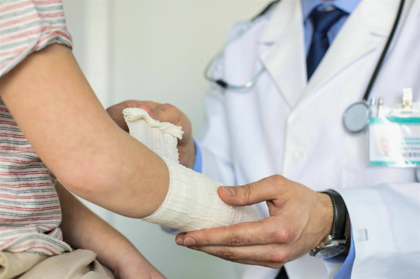 Pédiatre attachant bandage sur la main du garçon à la clinique
 - Photo, image